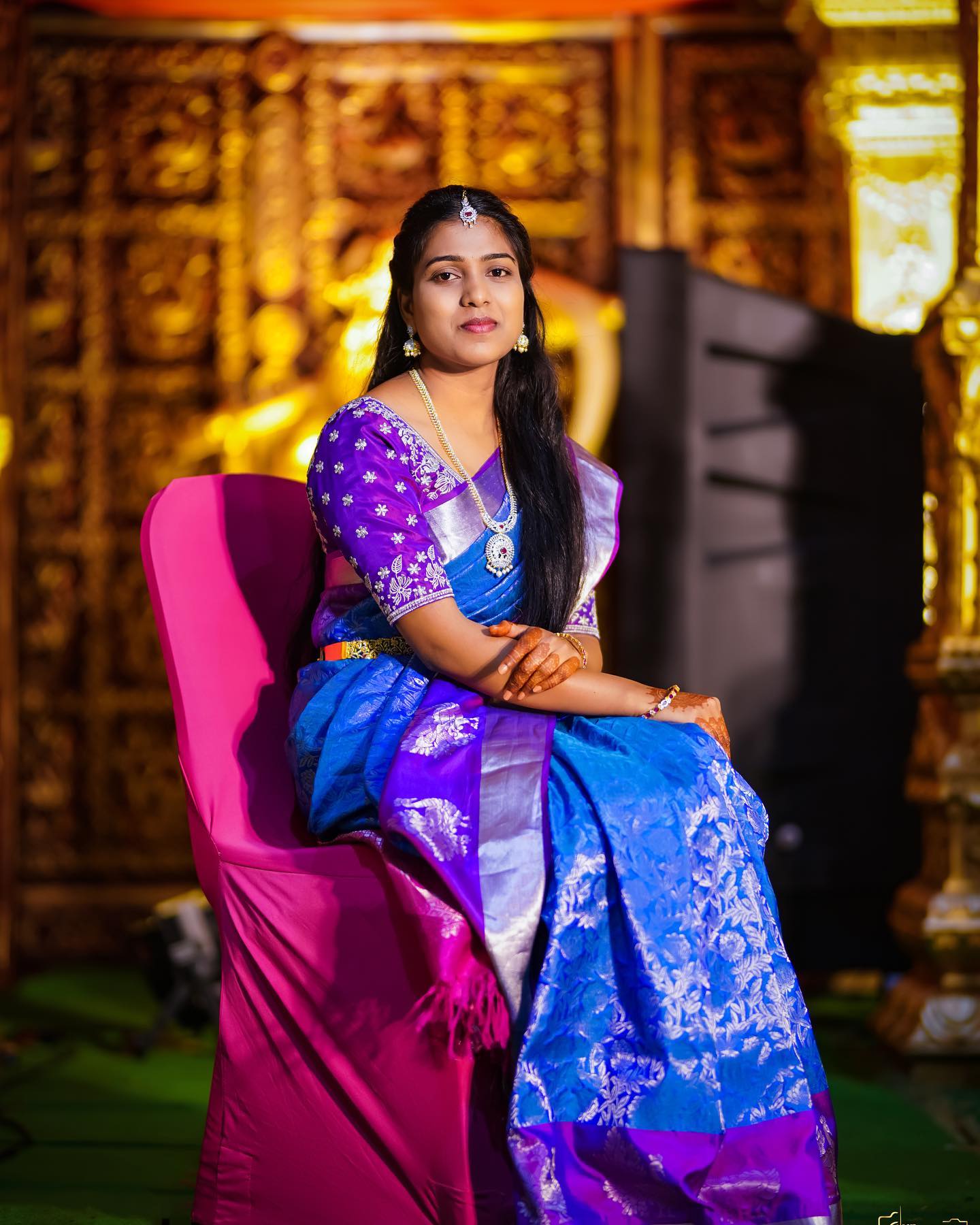 A bride in a blue and purple sari seated for a wedding portrait